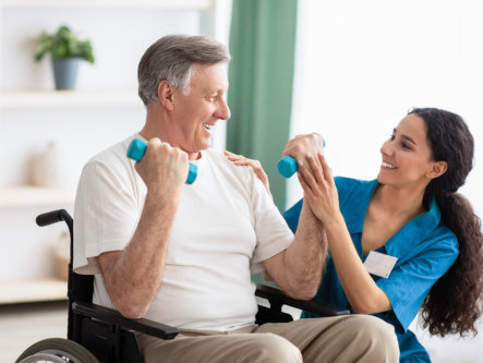 nurse assisting elderly man doing dumbbell