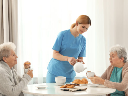 nurse assisting the two elderly woman