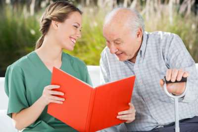 nurse and elderly man looking at the notebook