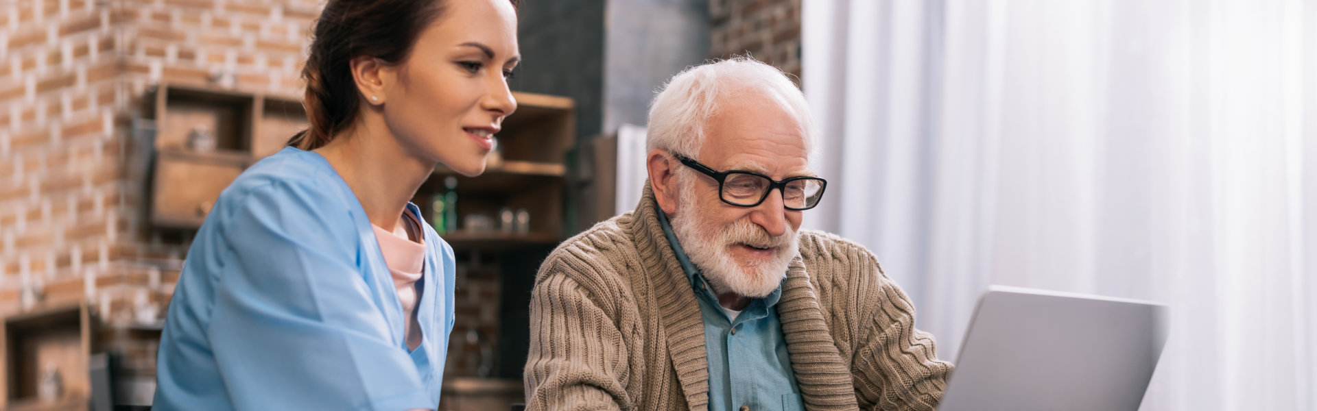 nurse and elderly man looking at the laptop