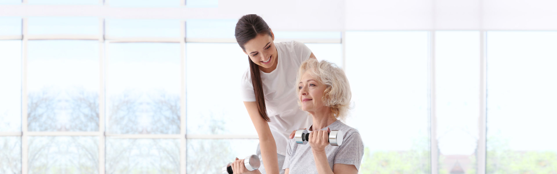 nurse assisting elderly woman doing dumbbell