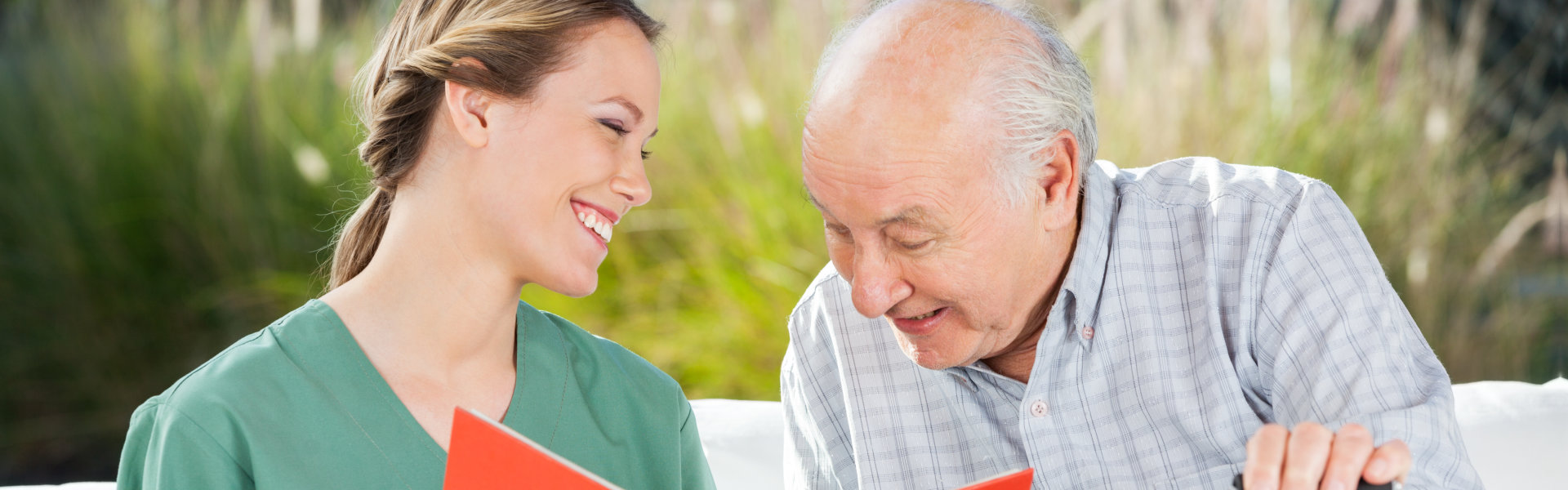 nurse and elderly man looking at the notebook