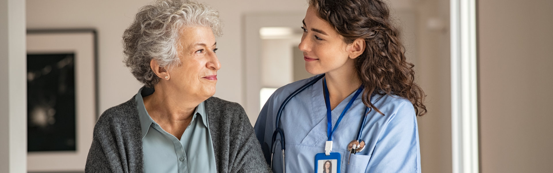 young caregiver helping senior woman walking